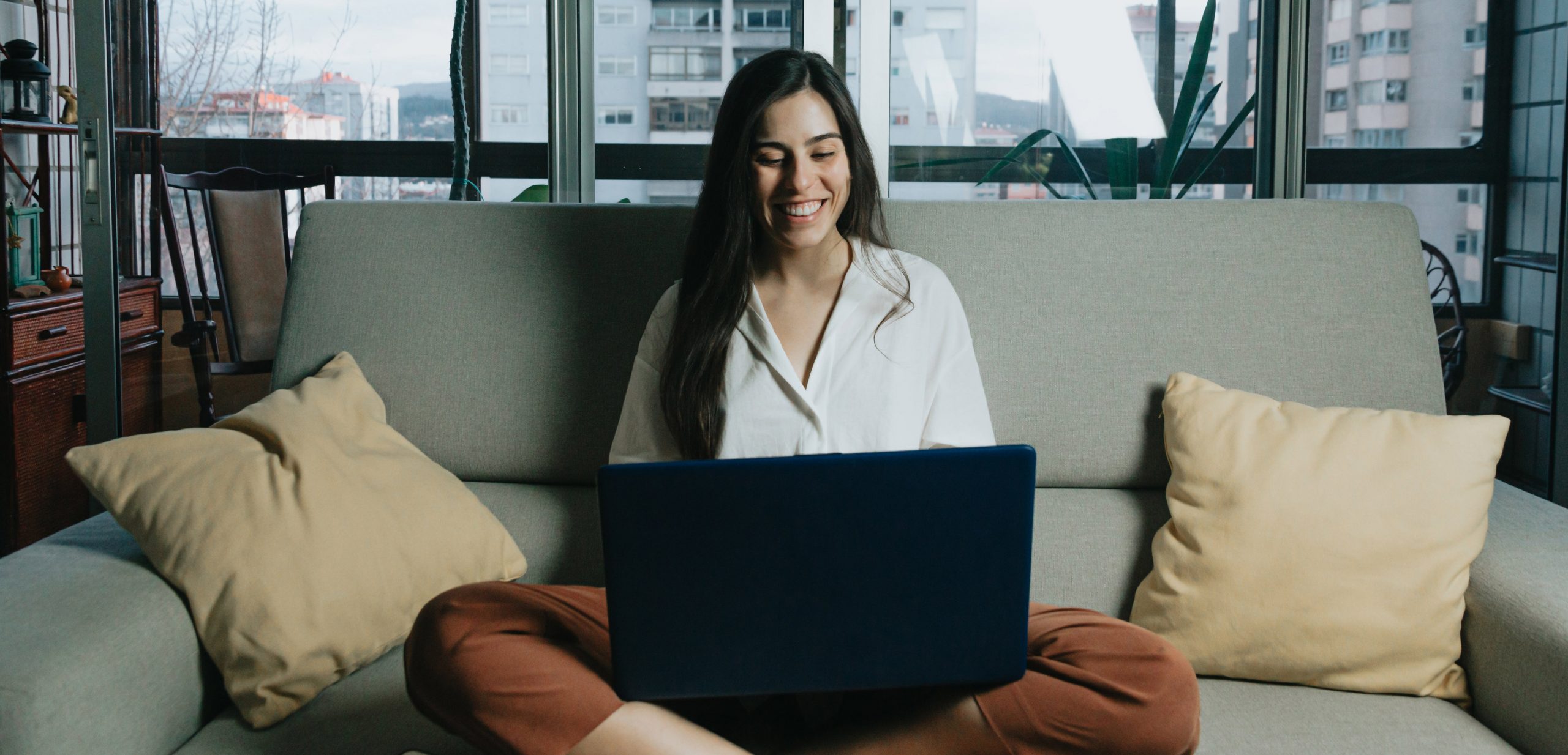 woman-sits-on-a-couch-while-looking-at-laptopAdjusted